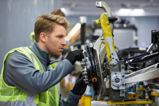homme sur une ligne de montage de pièces automobiles