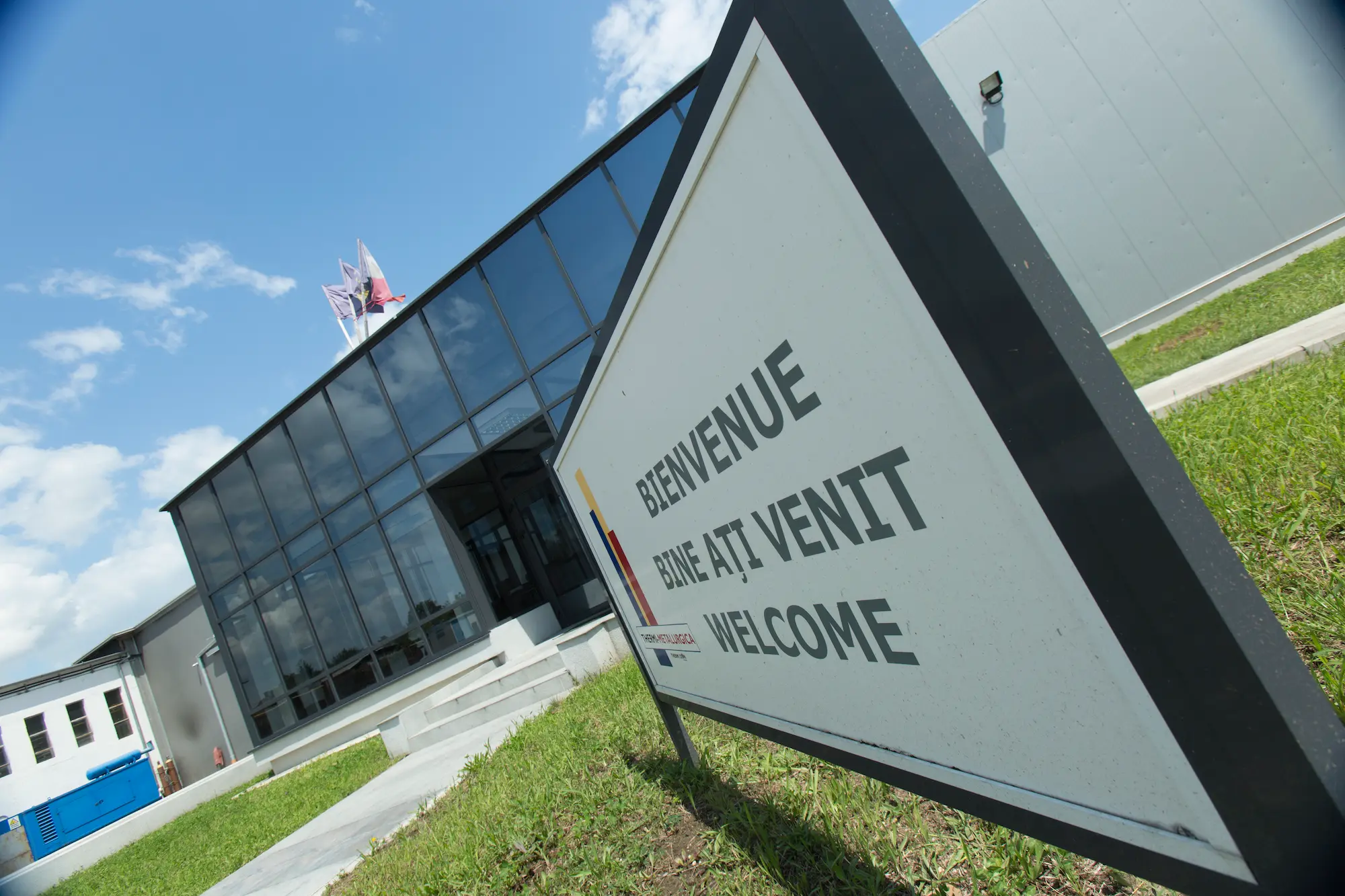 entrée de l'usine thermi-metalurgica avec un panneau en trois langues : roumain, français et anglais