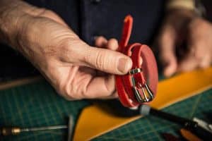 image d'une ceinture en cuir rouge avec une boucle métallique pour illustrer les traitements PVD au service des secteurs du luxe et du décoratif